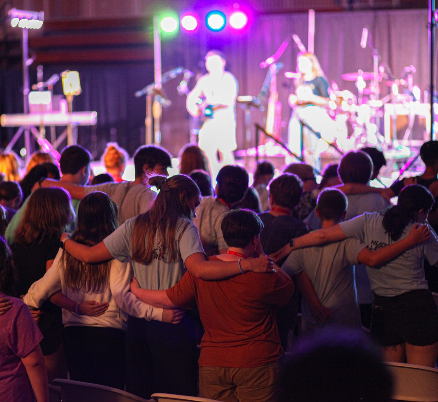 Middle and high school students fully engaged in worship as they worship together as a small group family during summer camp at summer games camp