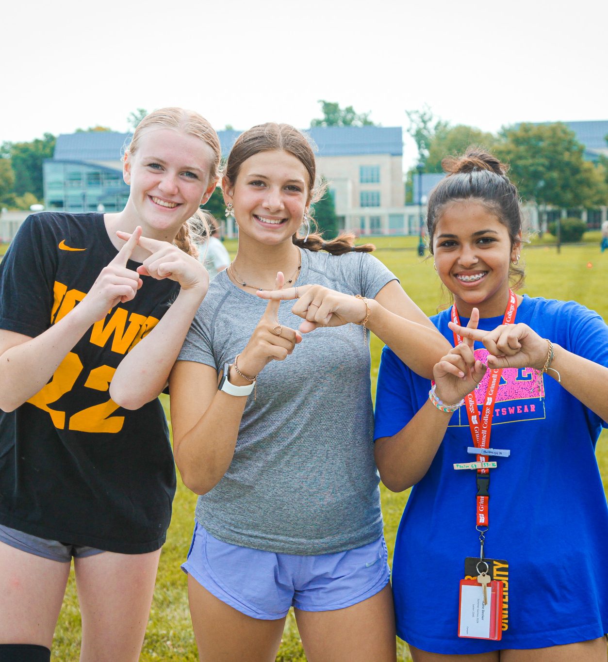 Three teen girls making crosses with the pointer fingers on each hands to demonstrate that the cross has made a difference in their lives.