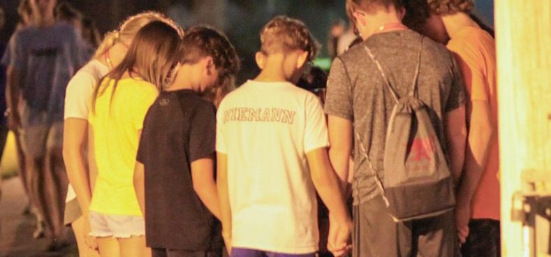 A group of middle school summer camp, middle school church camp students stop to pray together after experiencing the crucifixion pageant.